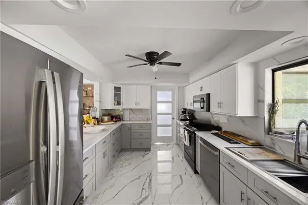 a kitchen with stainless steel appliances a refrigerator a sink a stove and white cabinets