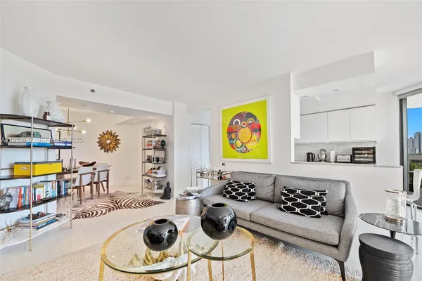 a living room with furniture kitchen view and a window