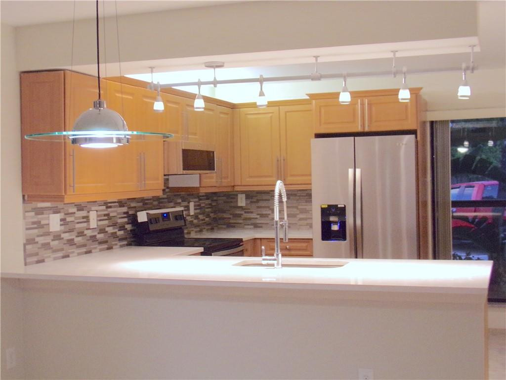 8205 Boca Rio Drive, Unit 8205 Boca Raton, FL 33433 - Photo 2 of 17 a kitchen with stainless steel appliances kitchen island granite countertop a refrigerator and a wooden cabinets