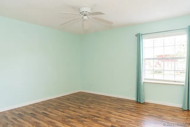 an empty room with a window and a ceiling fan