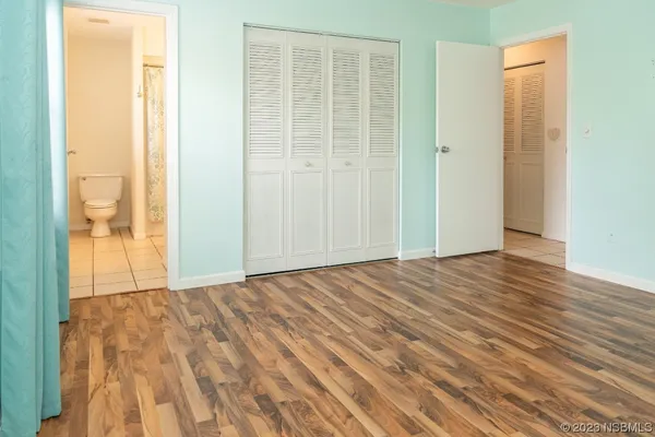 a view of an empty room with wooden floor and a bathroom