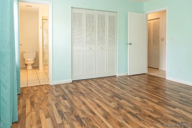 a view of an empty room with wooden floor and a bathroom