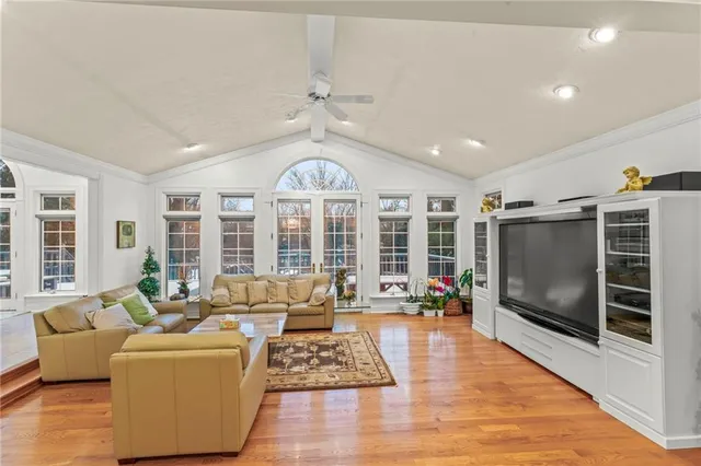a living room with furniture a flat screen tv and a floor to ceiling window or wooden floor