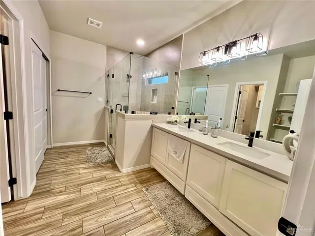 a bathroom with a double vanity sink mirror and shower