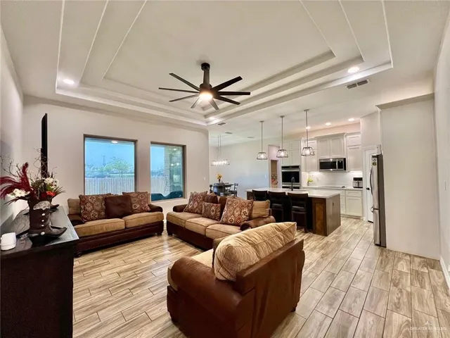 a living room with furniture kitchen view and a wooden floor