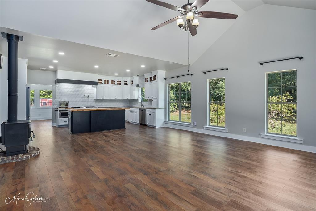 550 Linton Bellevue Road Benton, LA 71006 - Photo 11 of 37 Kitchen featuring an island, backsplash, high vaulted ceiling, dark wood laminate floors, and a wood burning stove