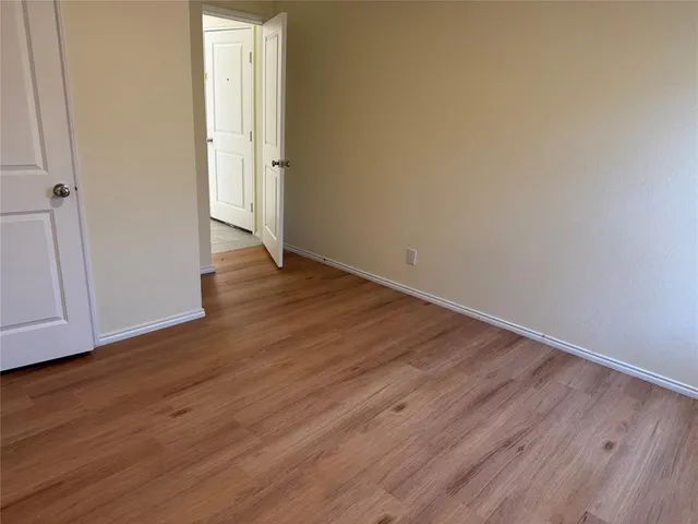 a view of an empty room with wooden floor and closet