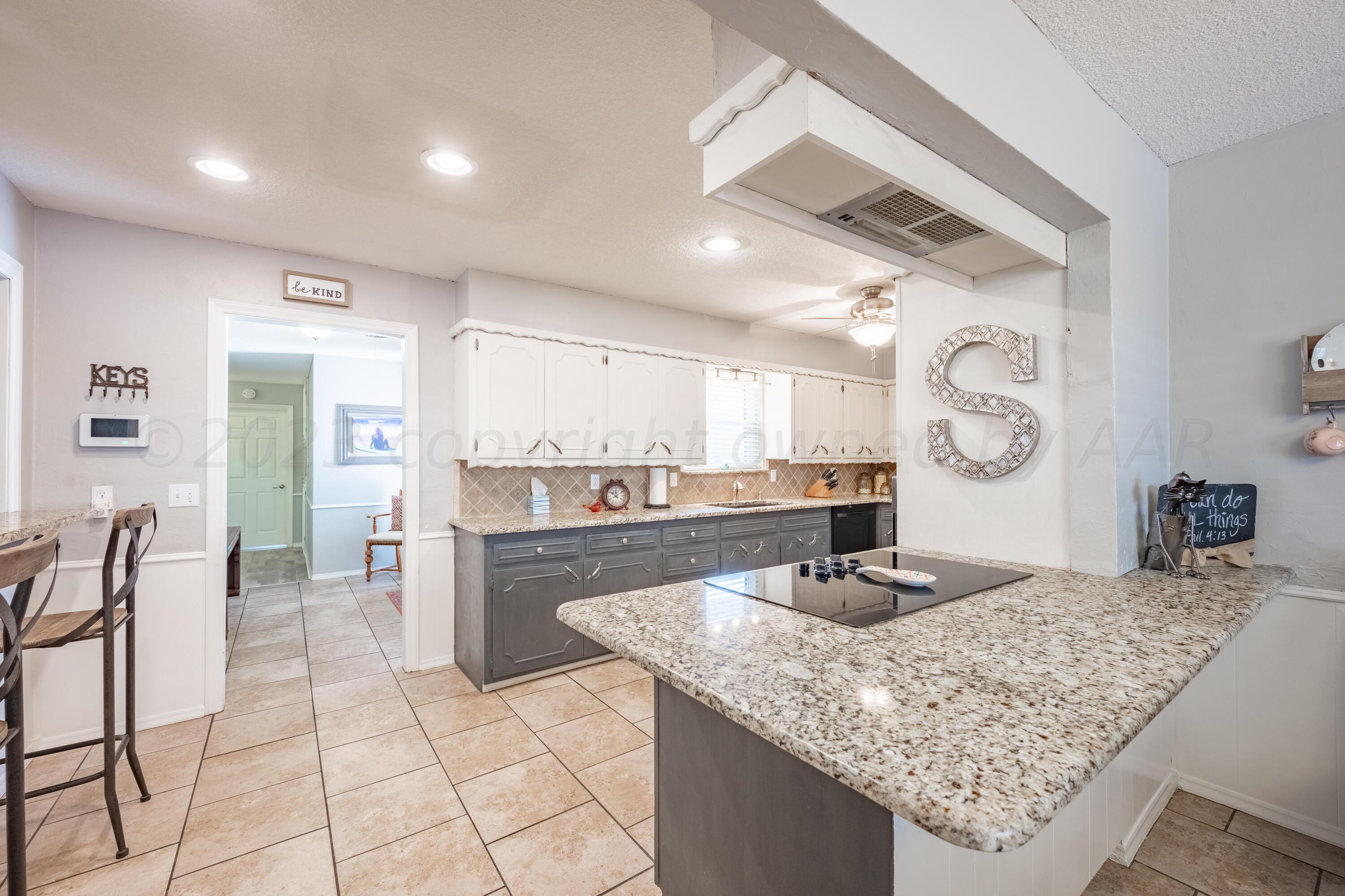 3313 Bedford Road Amarillo, TX 79106 - Photo 7 of 24 a kitchen with granite countertop a sink a stove top oven a clock and cabinets