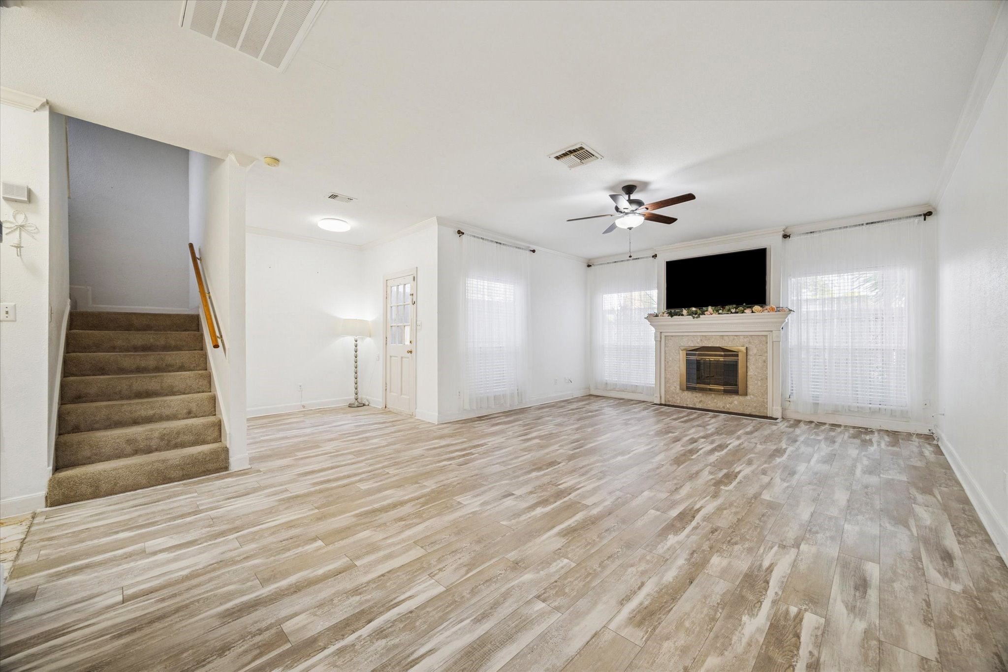 880 Tully Street, Unit 13 Houston, TX 77079 - Photo 13 of 27 a view of a livingroom with a flat screen tv staircase and a ceiling fan