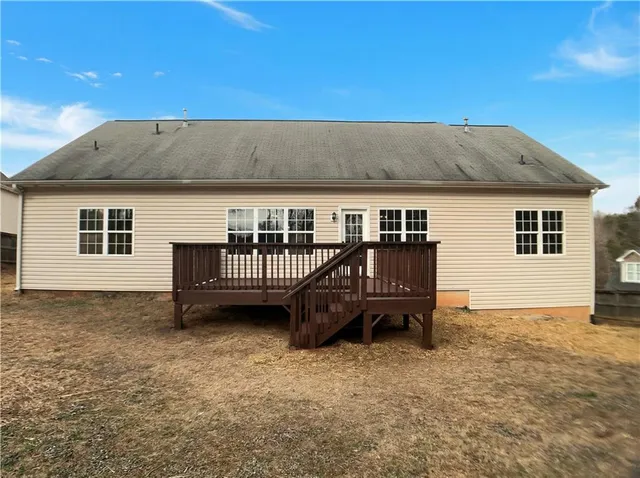 a view of a house with wooden deck and a barbeque