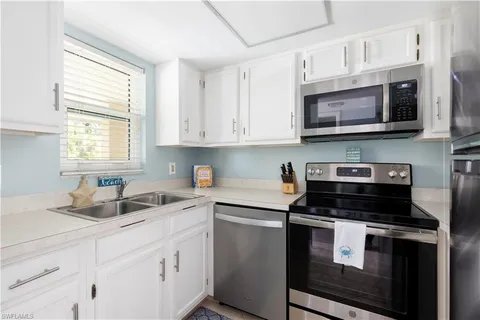 a kitchen with stainless steel appliances granite countertop white cabinets a stove a sink and a microwave