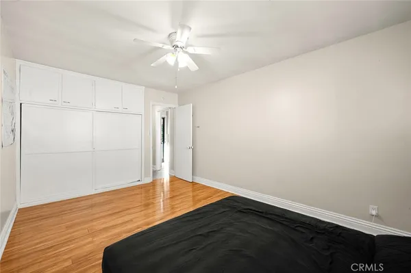 an empty room with wooden floor closet and fan