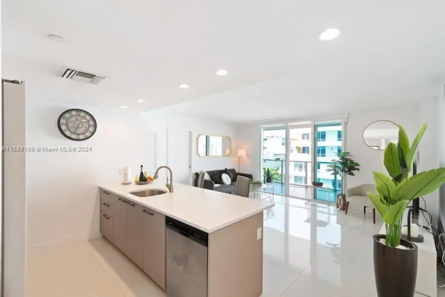 a kitchen with a sink a counter and a living room view