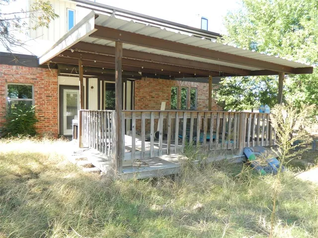 a backyard of a house with table and chairs floor to ceiling window and wooden fence