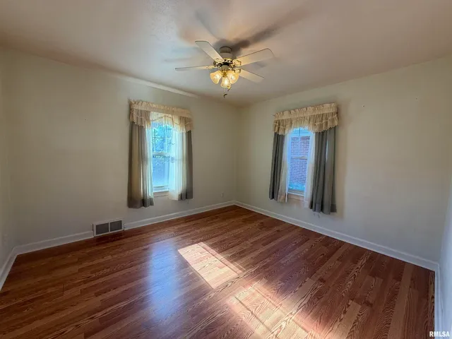 a view of an empty room with window and wooden floor