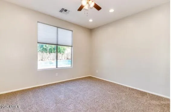 a view of an empty room with window and a ceiling fan