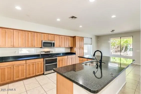 a kitchen with stainless steel appliances granite countertop a sink a stove and wooden cabinets