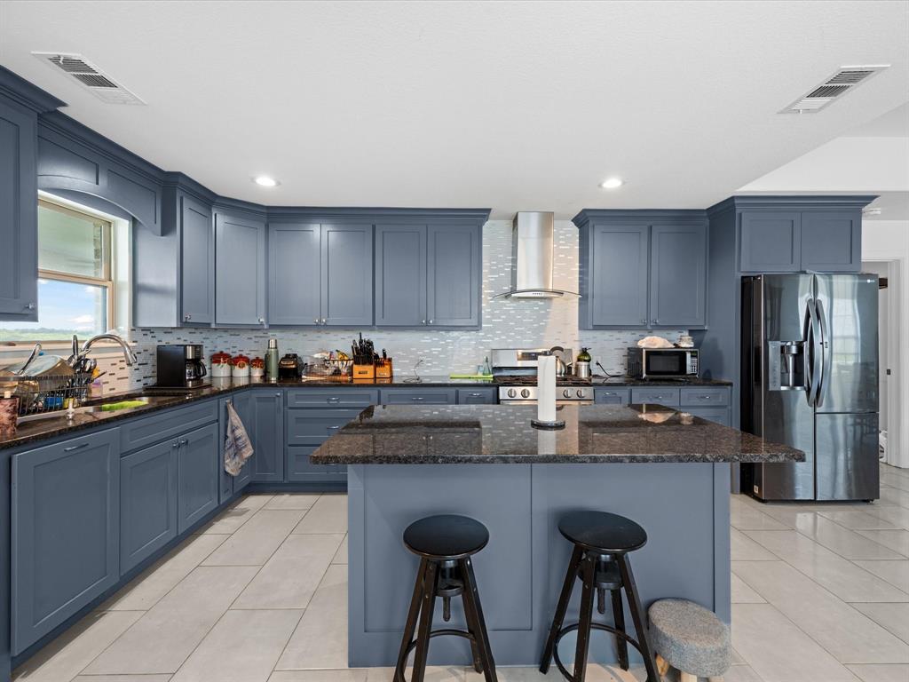 781 Alsdorf Road Ennis, TX 75119 - Photo 27 of 39 a kitchen with granite countertop a table chairs microwave and refrigerator