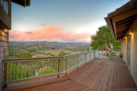 a view of a roof deck with table and chairs a barbeque with wooden floor and fence