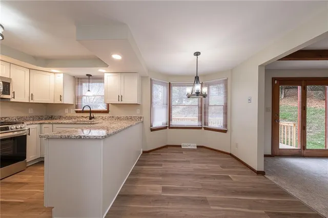 a large kitchen with granite countertop a large counter top space a sink stainless steel appliances and cabinets