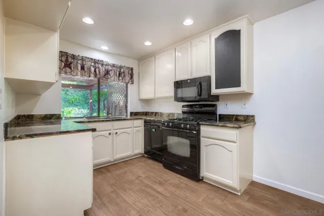 a kitchen with stainless steel appliances granite countertop a stove a sink and a microwave