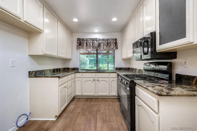 a kitchen with stainless steel appliances granite countertop a stove a sink and a microwave