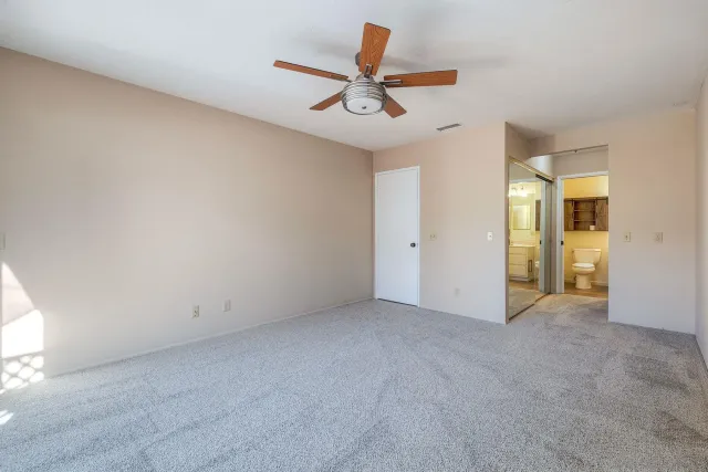 an empty room with closet and a ceiling fan