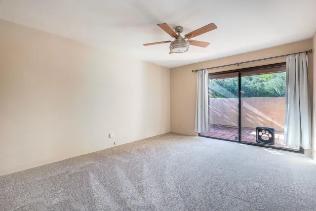 an empty room with windows and view of a ceiling fan