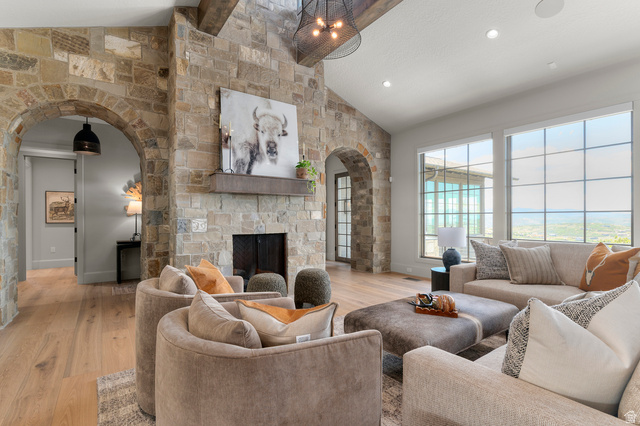 2192 East Outlaw Road Kamas, UT 84036 - Photo 25 of 80 Stone fireplace with a wood mantel, vaulted ceiling with exposed wood beams, and a black wrought iron chandelier