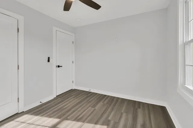 an empty room with wooden floor cabinet and windows