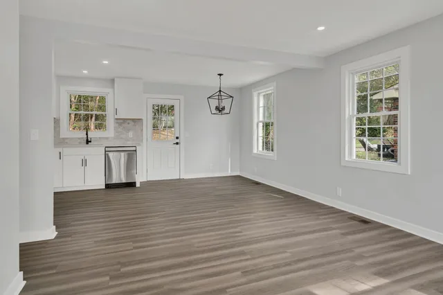 an empty room with wooden floor cabinet and windows