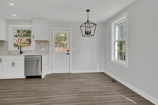 a view of hallway with chandelier and wooden floor