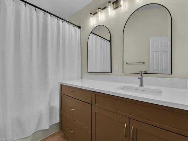 a bedroom with a bed a chandelier and dresser