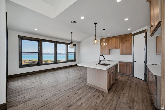 300 Knoll Loop, Unit 227 Fish Haven, ID 83287 - Photo 9 of 56 Kitchen featuring lofted ceiling, hanging light fixtures, a center island with sink, wood finish cabinetry, and light wood finished floors