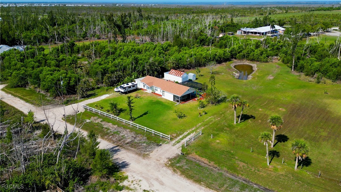 an aerial view of a residential houses with outdoor space and trees all around