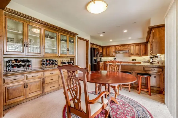 a kitchen with stainless steel appliances kitchen island granite countertop a stove a sink a dining table and chairs with wooden floor