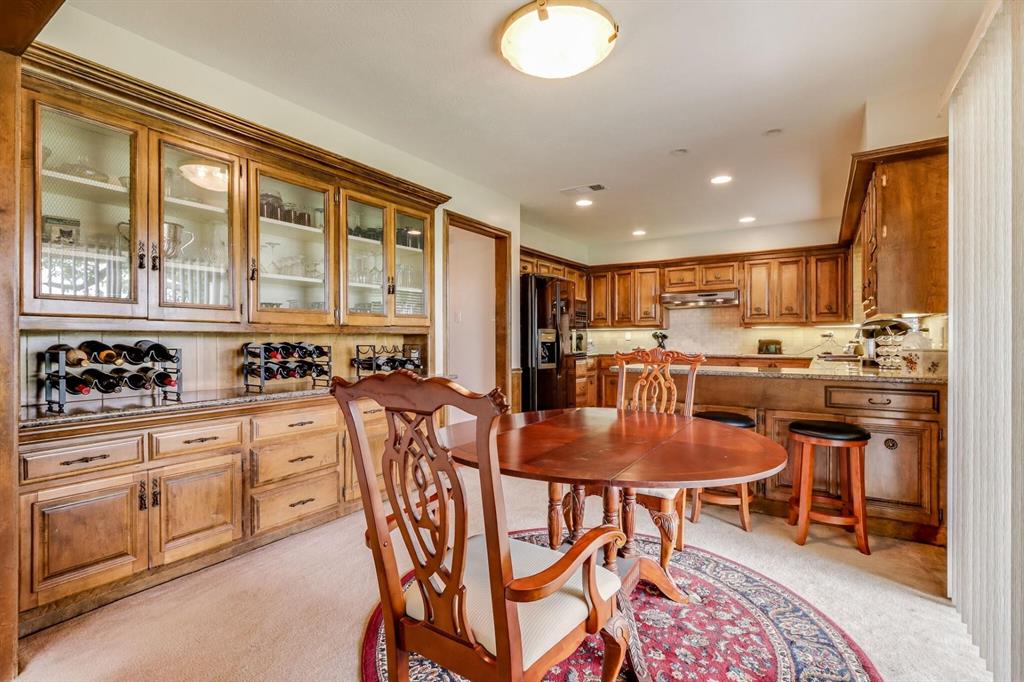 9310 Waterview Road Dallas, TX 75218 - Photo 12 of 35 a kitchen with stainless steel appliances kitchen island granite countertop a stove a sink a dining table and chairs with wooden floor