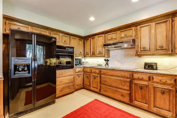 a kitchen with stainless steel appliances granite countertop a refrigerator and a stove top oven