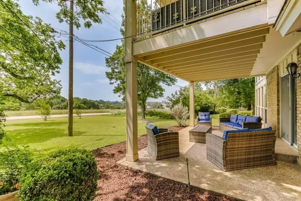 a view of a patio with table and chairs potted plants and floor to ceiling window
