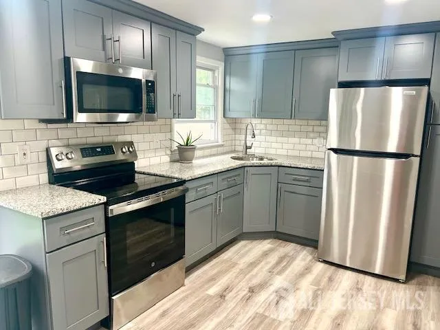 a kitchen with stainless steel appliances granite countertop a refrigerator a stove a sink and a microwave