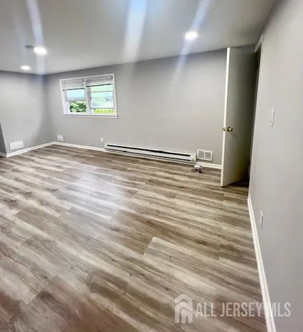 an empty room with wooden floor and window