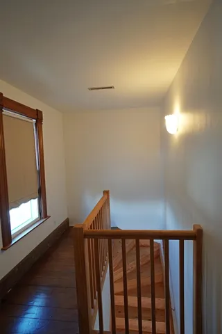 a view of hallway with window and wooden floor