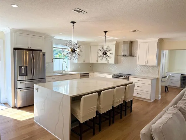 a open kitchen with stainless steel appliances granite countertop a sink a stove a refrigerator and island with wooden floor