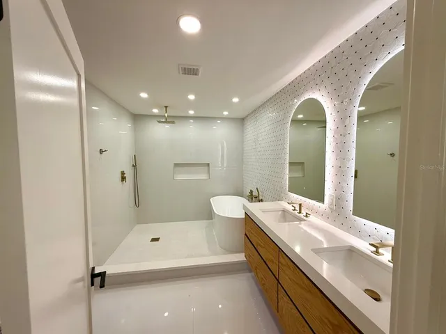 a spacious bathroom with a double vanity sink a mirror and a bathtub
