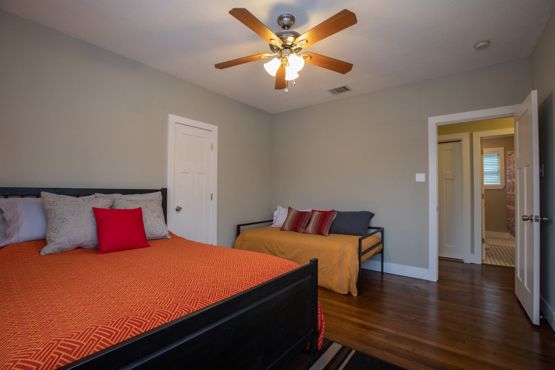 702 West N Loop Boulevard Austin, TX 78751 - Photo 5 of 23 Hardwood floors and a ceiling fan create a comfortable and inviting atmosphere in this cozy sleeping space.