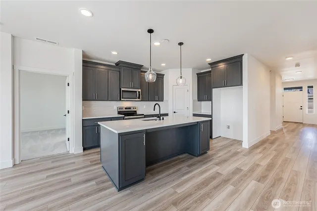 a large kitchen with a large counter top a sink stainless steel appliances and cabinets