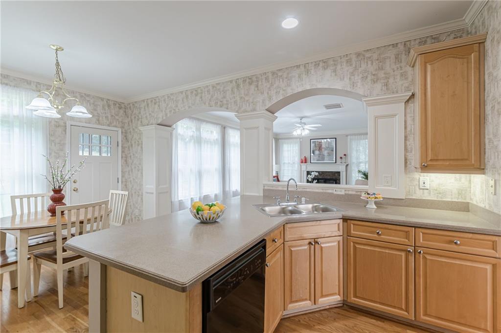 700 James Madison Drive South Fulton, GA 30331 - Photo 19 of 57 a kitchen with a sink dishwasher a stove a dining table and chairs with wooden floor