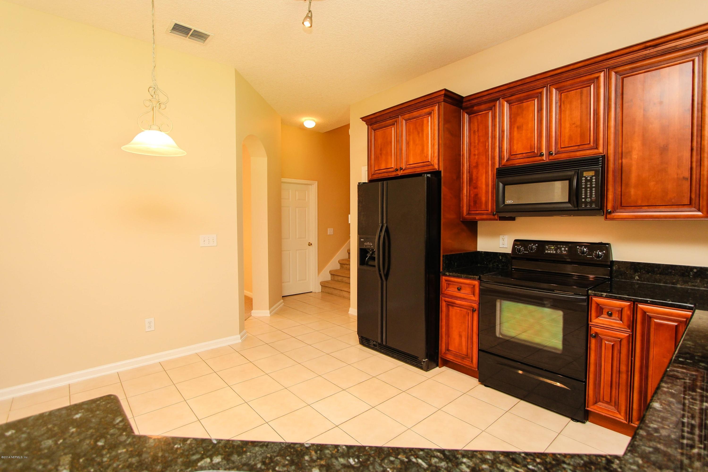 1252 Ribbon Road St. Johns, FL 32259 - Photo 14 of 27 a kitchen with stainless steel appliances granite countertop a refrigerator a stove and a sink with wooden cabinets