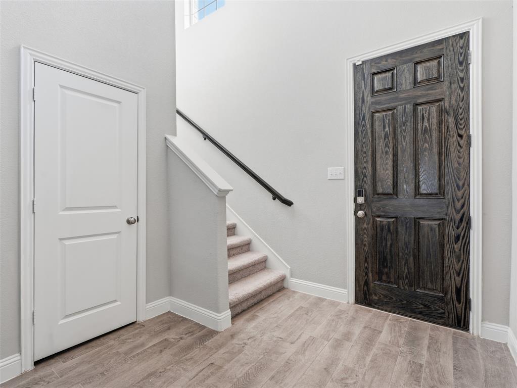Wood-finish flooring with a multi-panel door and a carpeted staircase