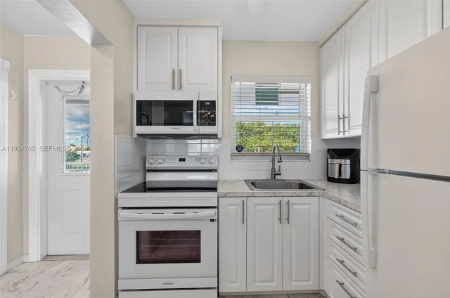 a kitchen with white cabinets and appliances